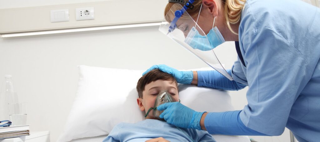 nurse puts oxygen mask on patient child in hospital bed