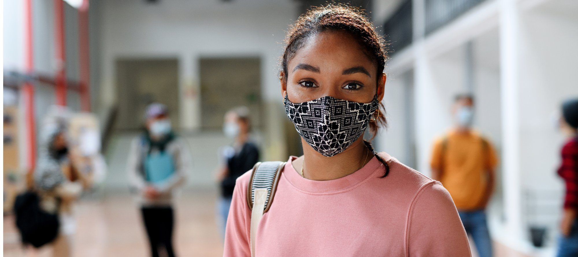 African-american student with face mask back at college