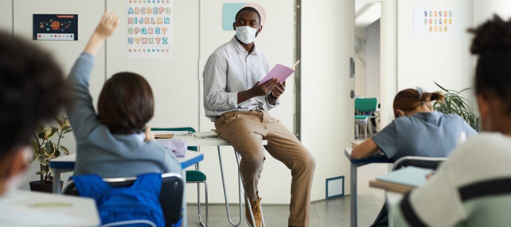 African-American teacher wearing mask in school classroom