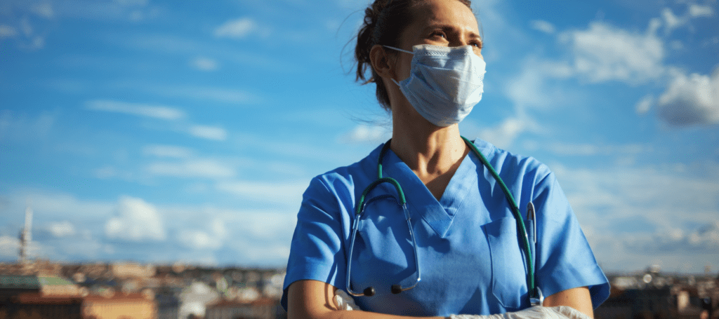 Healthcare worker standing confidently with arms crossed on rooftop in city