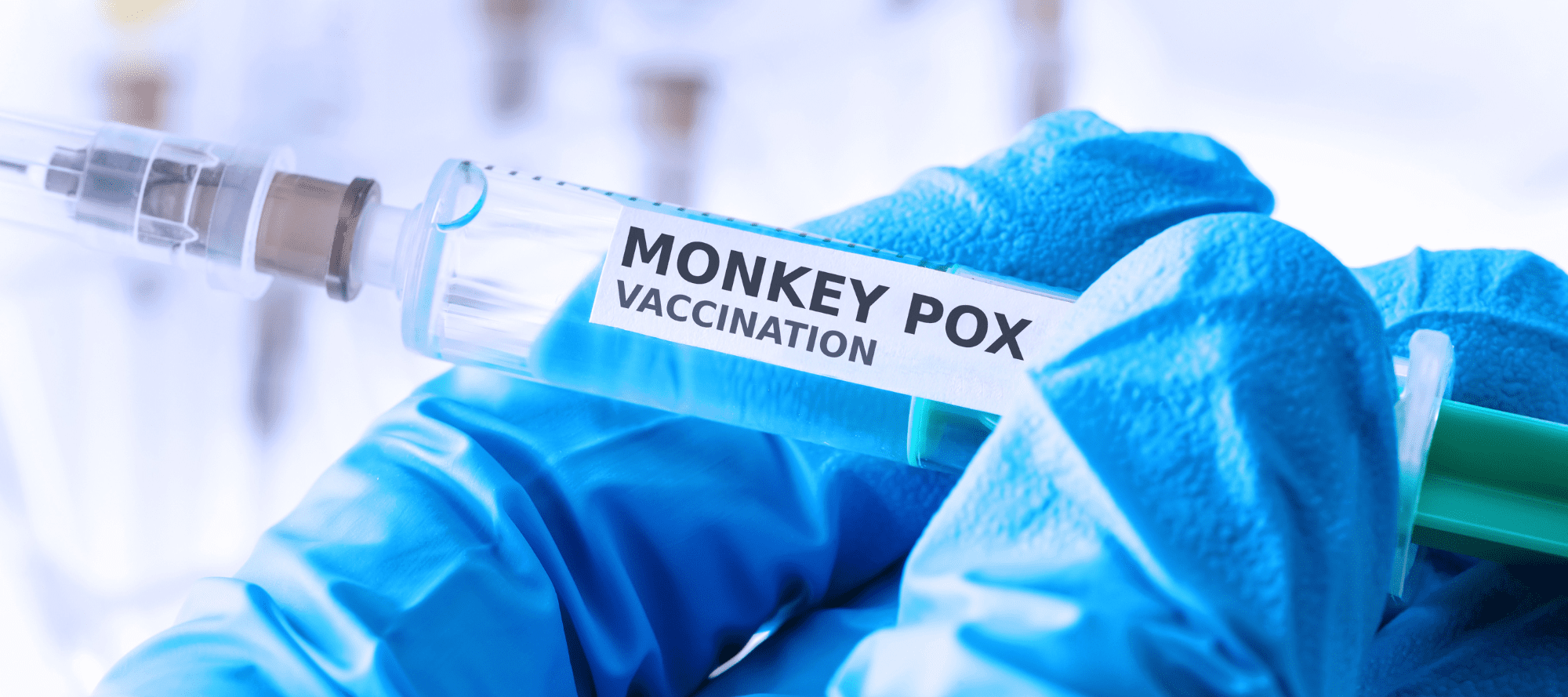 Person wearing medical grade gloves holding a filled syringe filled with Monkey Pox vaccine