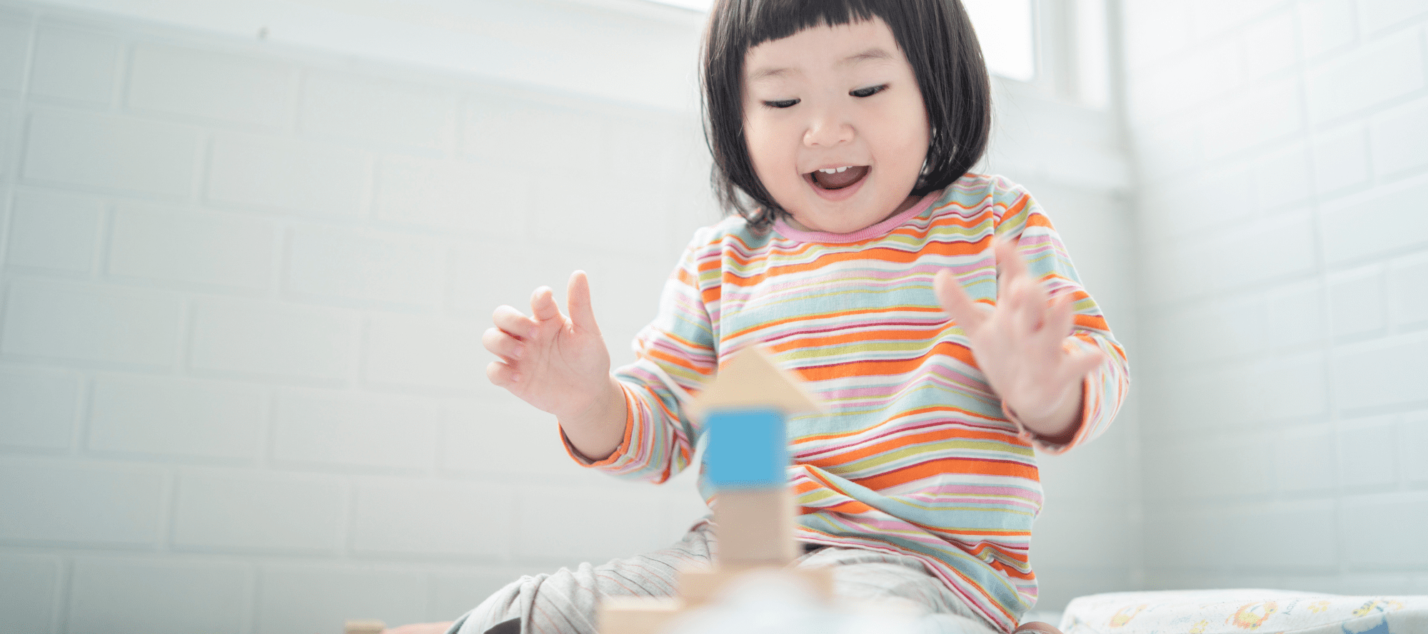 Child with Asian background playing with educational wooden toys