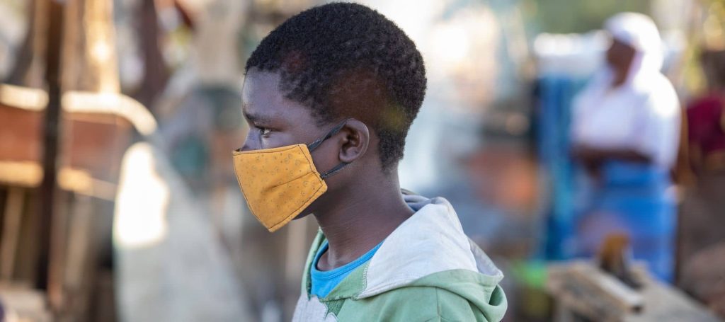 Young African child with mask on as he walks through town