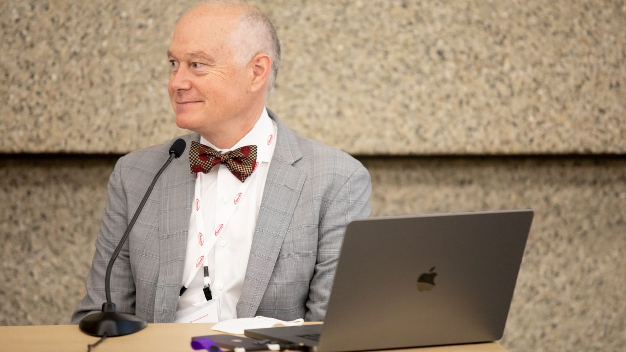 Dr. Griffin sitting on panel with his laptop open smiling