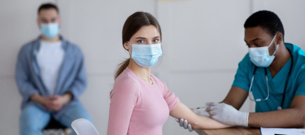 Young woman receiving a vaccine injection in her arm